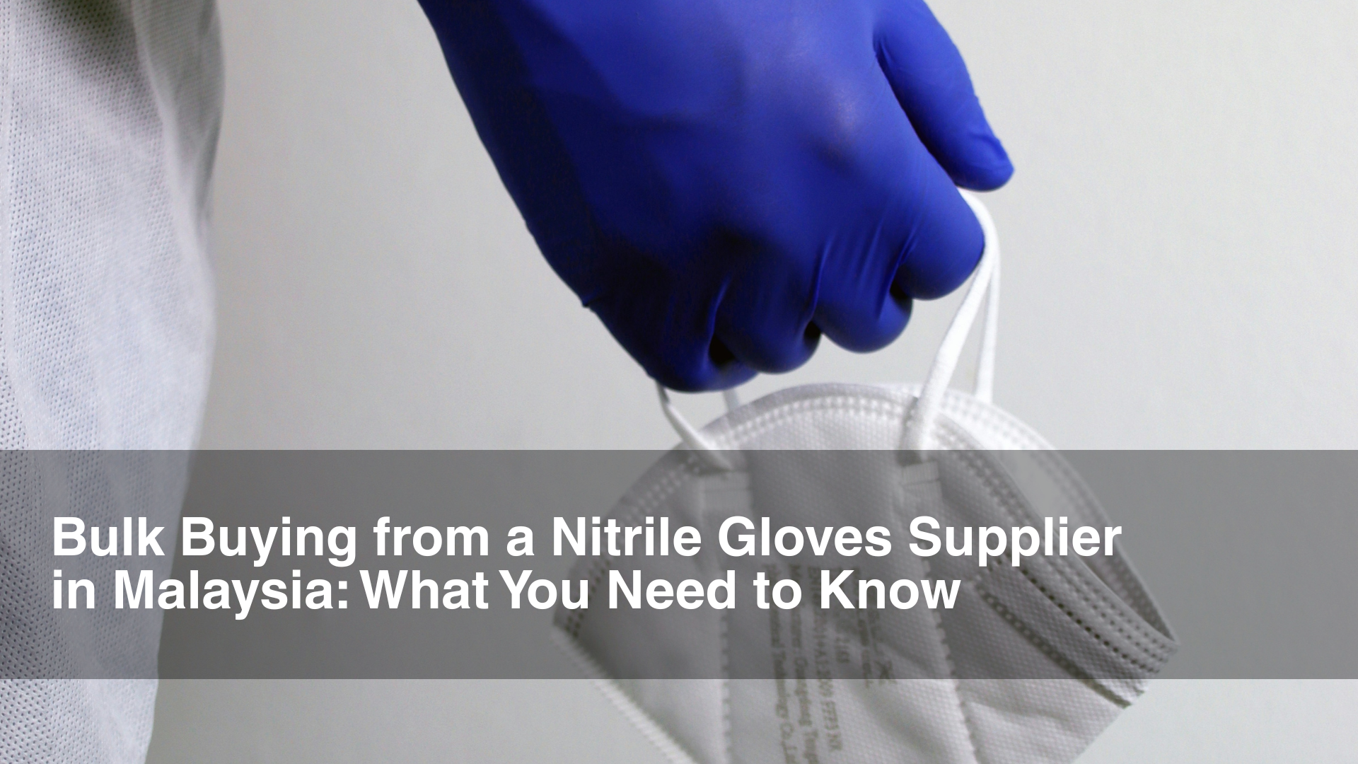 Doctor in PPE equipment and blue nitrile gloves holds up mask